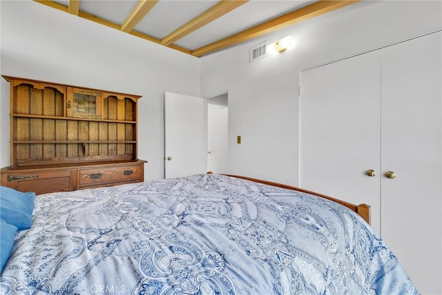 bedroom featuring beamed ceiling and visible vents