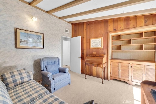 living room featuring wallpapered walls, beamed ceiling, visible vents, and light carpet