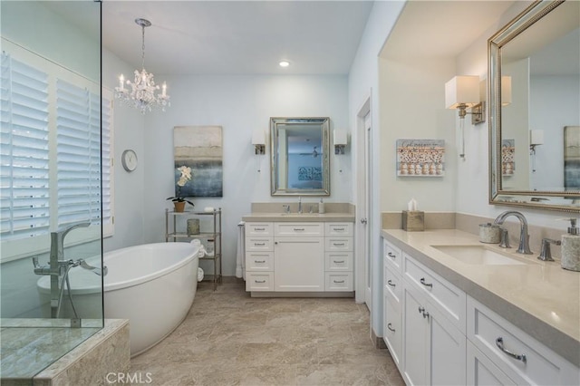 bathroom with a sink, a notable chandelier, a soaking tub, and two vanities