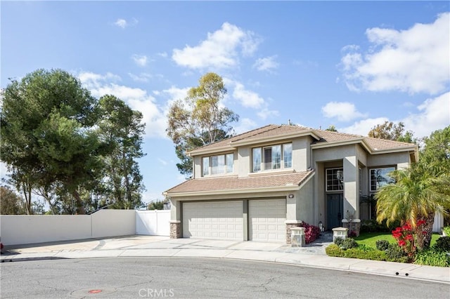 view of front of house with fence, driveway, an attached garage, stucco siding, and a tiled roof