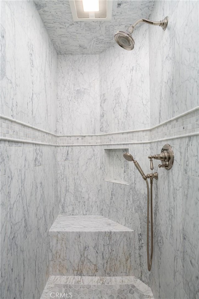 interior details featuring a marble finish shower and visible vents