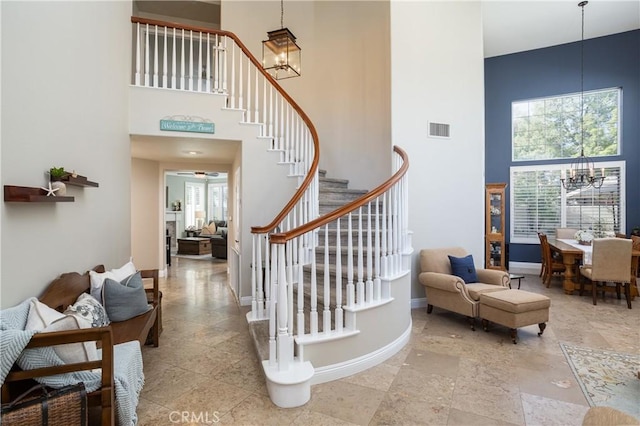 stairs with visible vents, baseboards, a high ceiling, and a chandelier