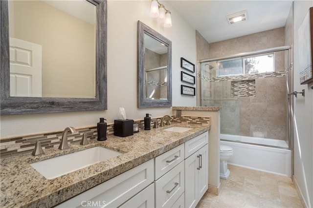 bathroom with a sink, combined bath / shower with glass door, toilet, and double vanity