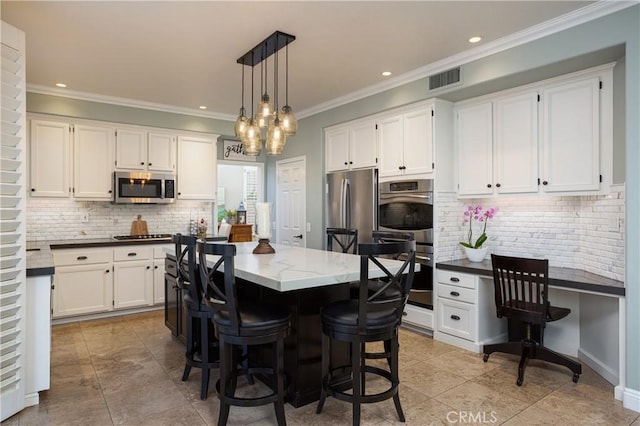 kitchen featuring visible vents, appliances with stainless steel finishes, built in study area, and white cabinetry