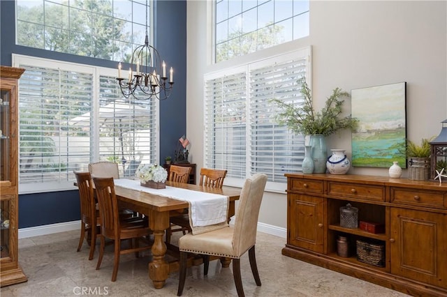 dining room with baseboards, a notable chandelier, and a high ceiling