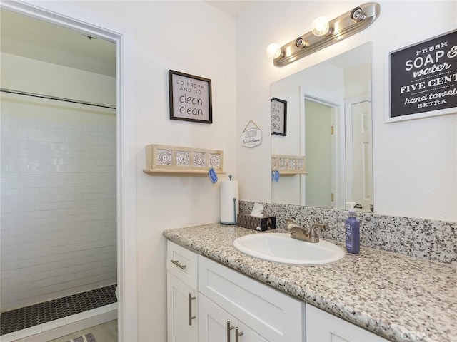 bathroom featuring tiled shower and vanity