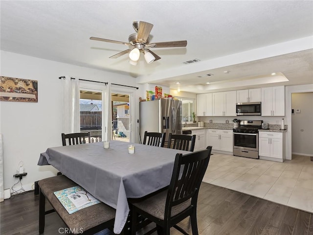 dining room featuring light wood-type flooring, visible vents, a ceiling fan, recessed lighting, and a raised ceiling