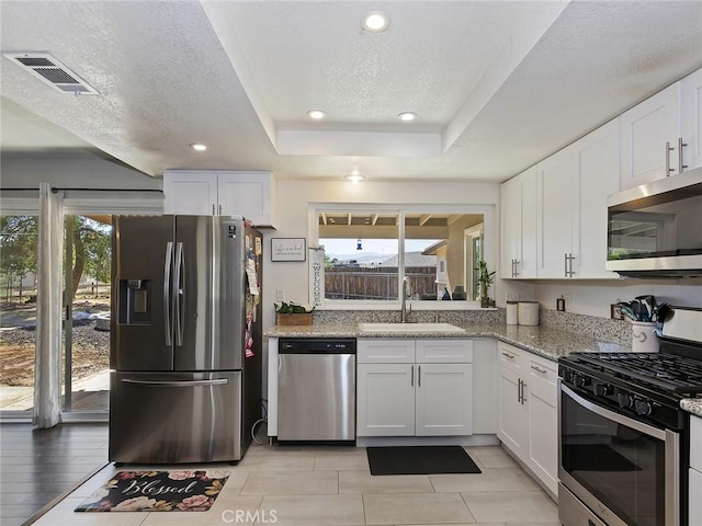 kitchen featuring visible vents, a sink, white cabinets, appliances with stainless steel finishes, and a textured ceiling