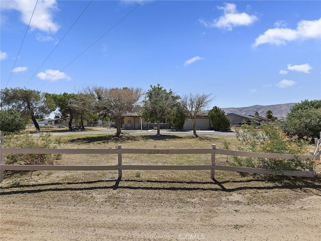 view of yard featuring a mountain view, a garage, driveway, and fence