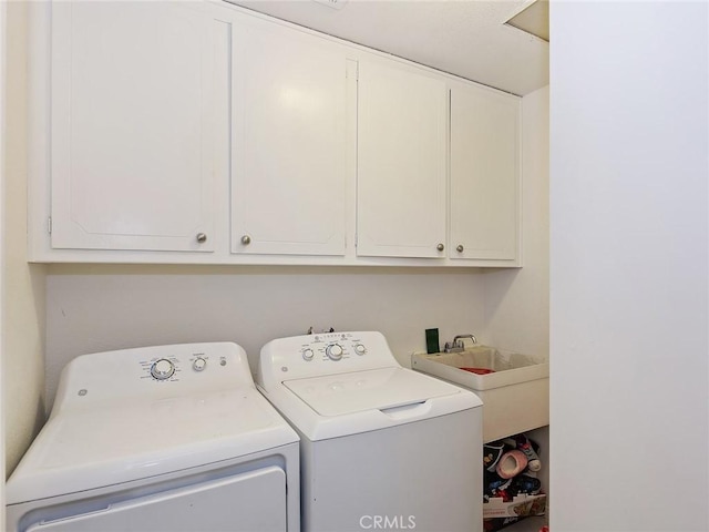 washroom with washing machine and clothes dryer, cabinet space, and a sink