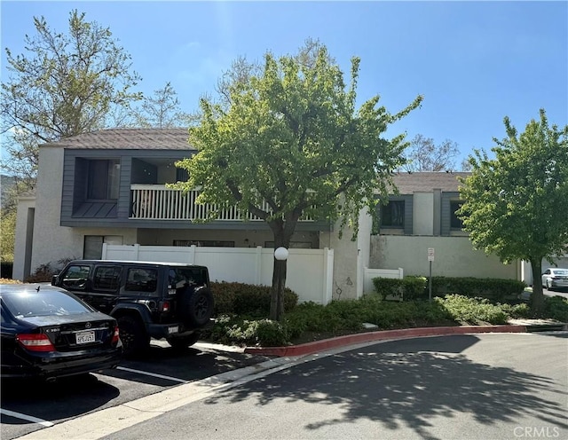 view of building exterior featuring fence and uncovered parking