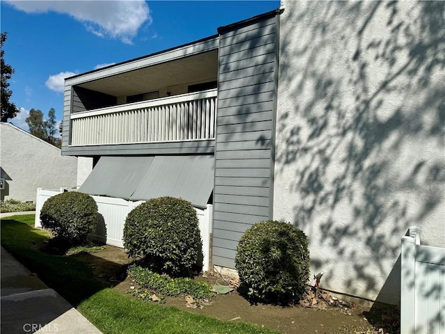 view of side of property featuring stucco siding and a balcony