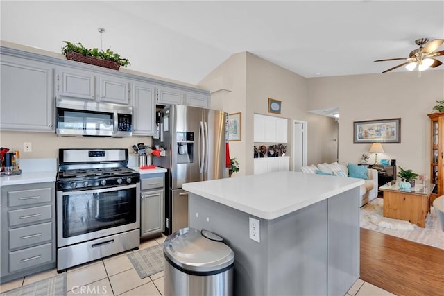 kitchen with lofted ceiling, gray cabinetry, light countertops, appliances with stainless steel finishes, and open floor plan