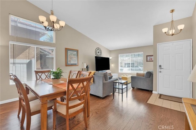 dining area with a notable chandelier, high vaulted ceiling, baseboards, and wood finished floors