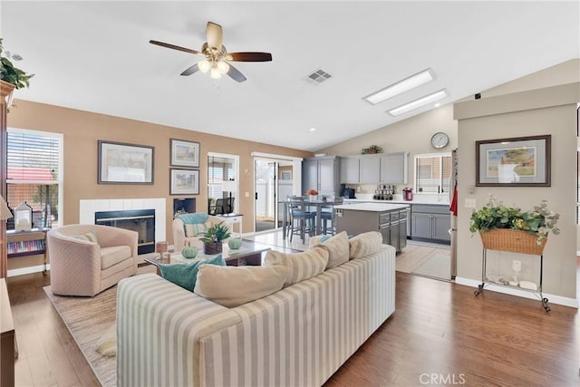 living area featuring visible vents, lofted ceiling, and wood finished floors