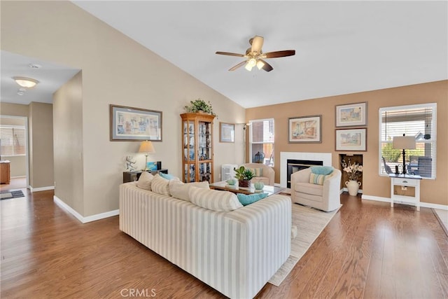 living room with a glass covered fireplace, plenty of natural light, lofted ceiling, and wood finished floors