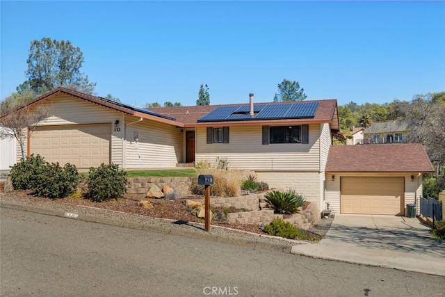 single story home with a garage, roof mounted solar panels, and concrete driveway