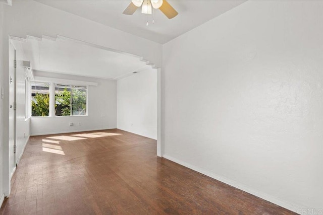 empty room featuring wood finished floors, baseboards, and ceiling fan