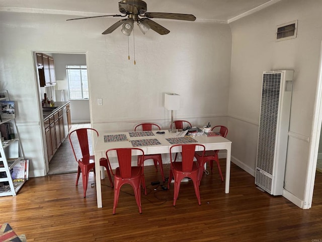 dining area with visible vents, wood finished floors, a heating unit, and a ceiling fan