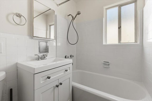 full bathroom with toilet, tile walls, vanity, and  shower combination