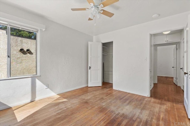 unfurnished bedroom with wood finished floors, a closet, a textured wall, and baseboards