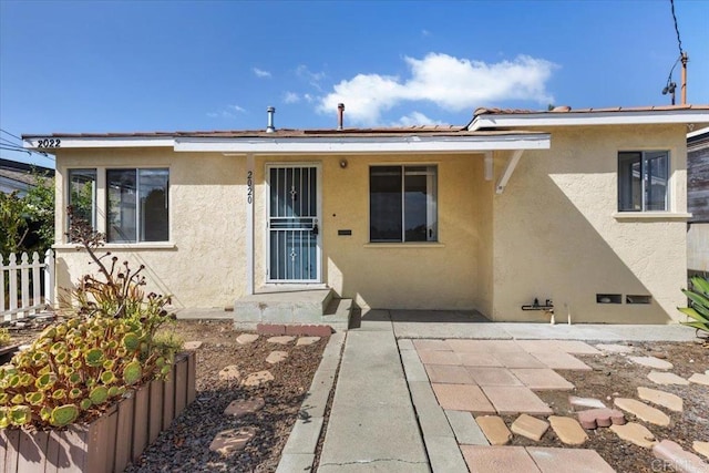 view of front facade with a patio area, stucco siding, and fence