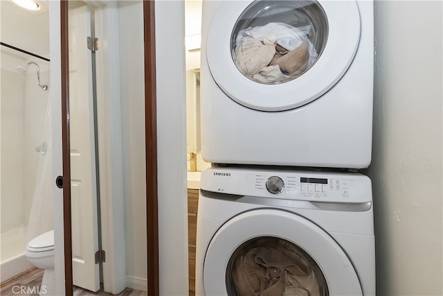 clothes washing area featuring stacked washer and clothes dryer and laundry area