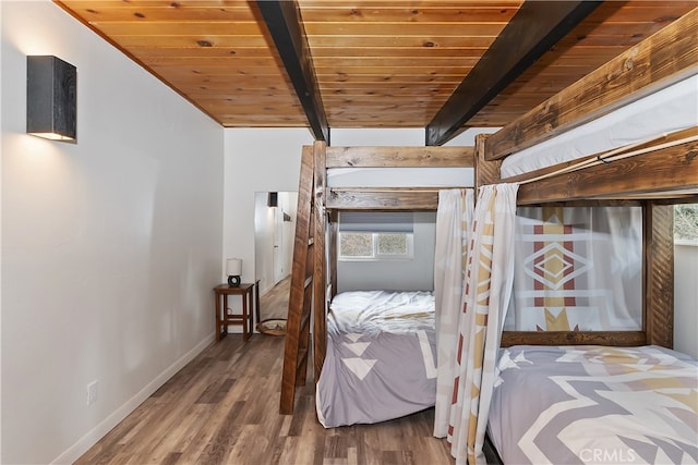 bedroom with beamed ceiling, wood ceiling, baseboards, and wood finished floors