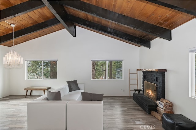 living room with beamed ceiling, a notable chandelier, wood finished floors, a brick fireplace, and wood ceiling