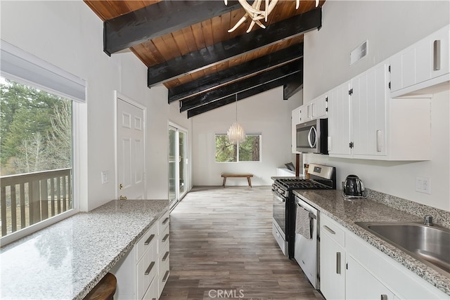 kitchen with visible vents, lofted ceiling with beams, appliances with stainless steel finishes, white cabinets, and a sink