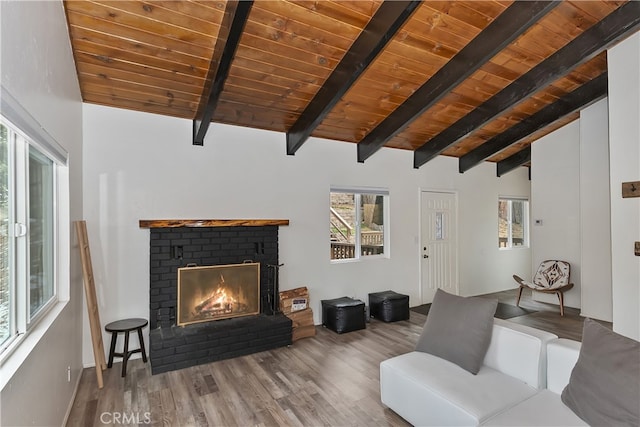 living room with lofted ceiling with beams, wood finished floors, a brick fireplace, and wooden ceiling