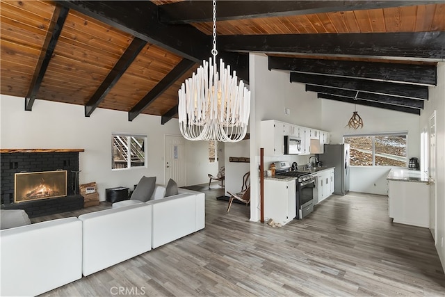 living area featuring wood ceiling, a brick fireplace, an inviting chandelier, and vaulted ceiling with beams