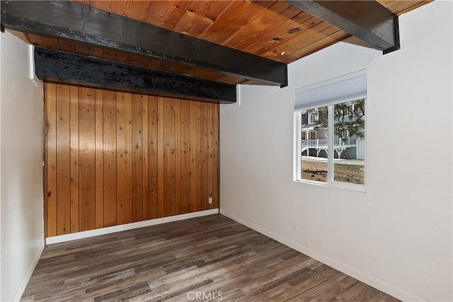 spare room with baseboards, beam ceiling, wood ceiling, and wood finished floors