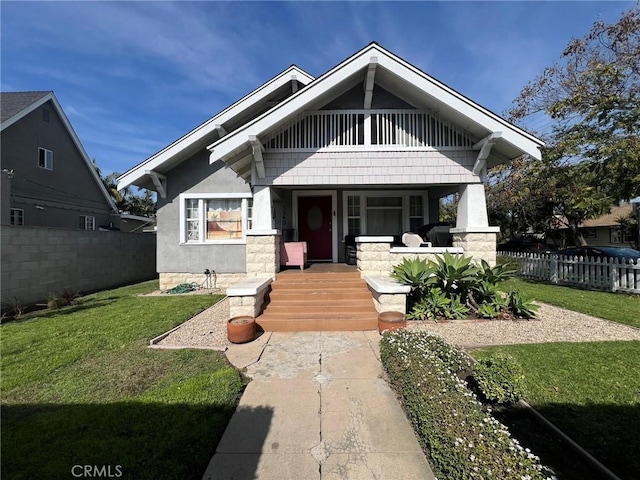 view of front of home featuring stucco siding, a porch, a front yard, and fence