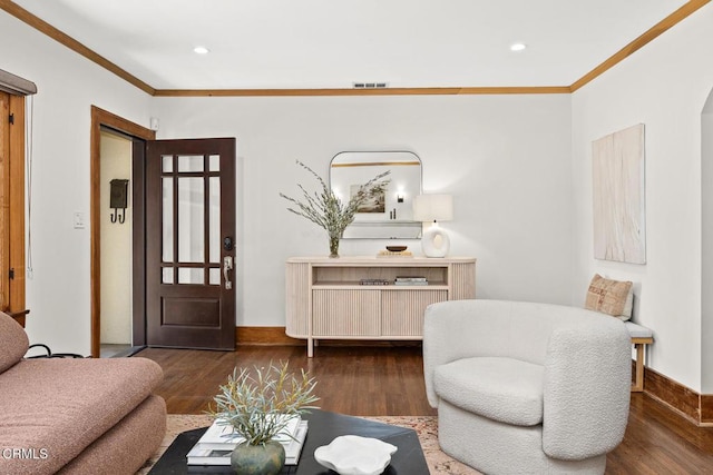 living room featuring visible vents, crown molding, baseboards, and wood finished floors