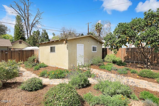 view of side of property featuring an outbuilding, fence, and stucco siding