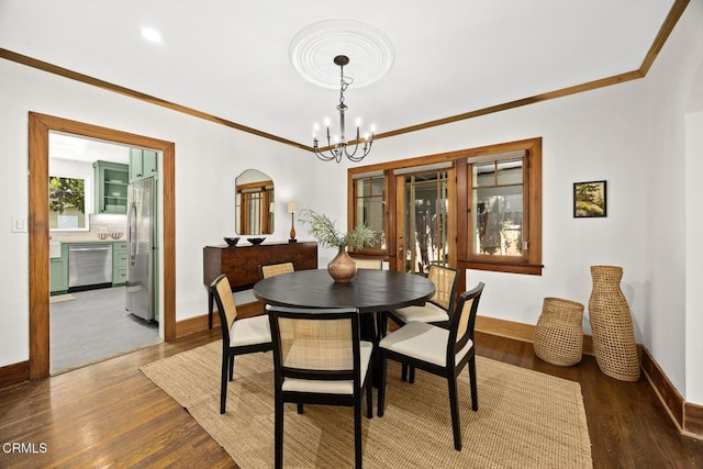 dining space with a notable chandelier, crown molding, baseboards, and wood finished floors