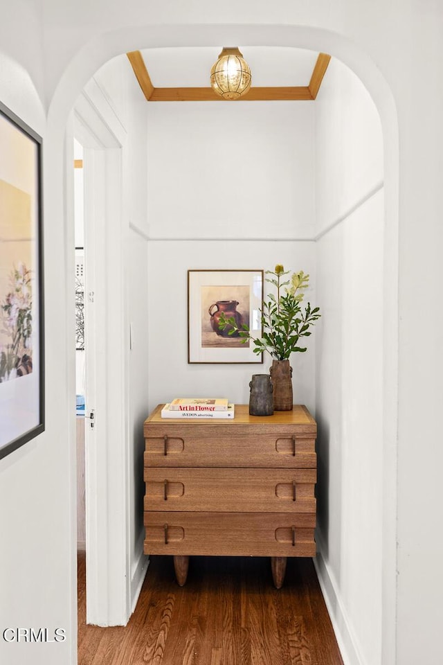 hallway with arched walkways, dark wood finished floors, and ornamental molding