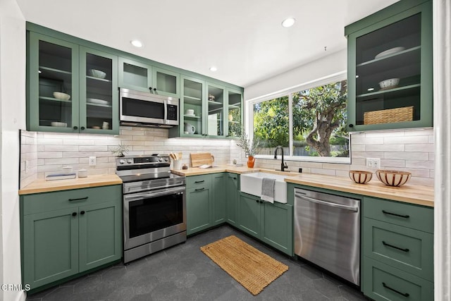 kitchen with a sink, butcher block counters, green cabinetry, and stainless steel appliances