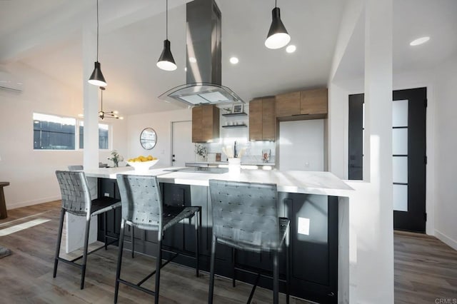 kitchen with brown cabinetry, dark wood-style floors, a wall mounted AC, island exhaust hood, and light countertops