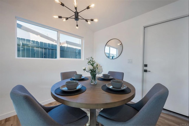 dining room with an inviting chandelier, vaulted ceiling, wood finished floors, and baseboards