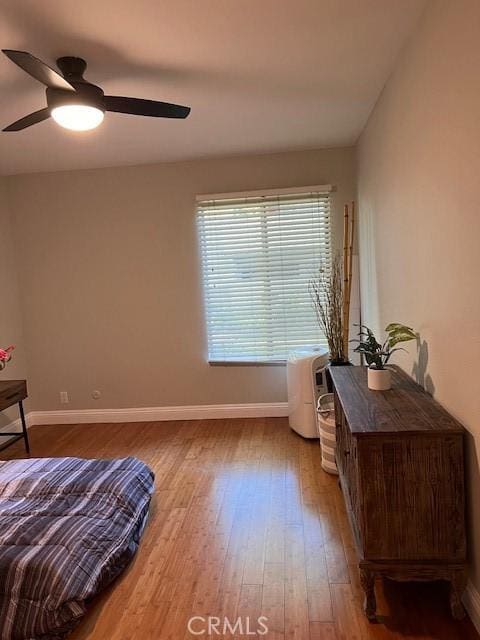 bedroom featuring baseboards, wood finished floors, and a ceiling fan