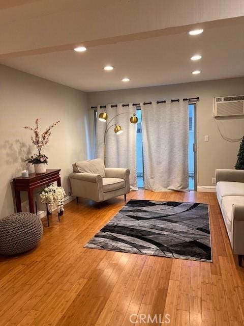 living area with recessed lighting, a wall mounted AC, and hardwood / wood-style flooring