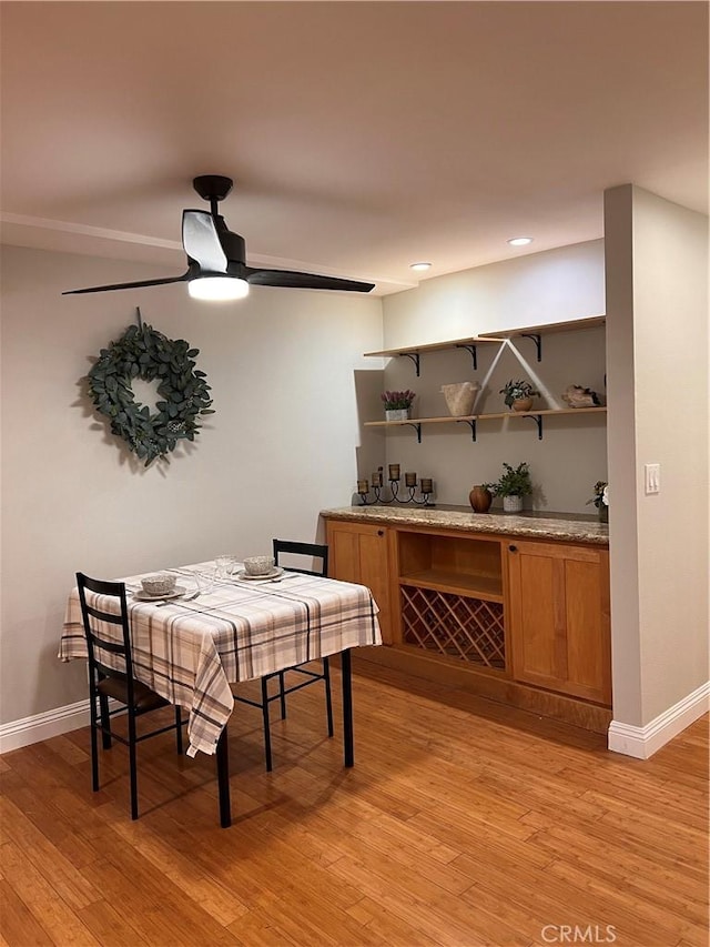 dining room featuring light wood-style flooring, a ceiling fan, and baseboards