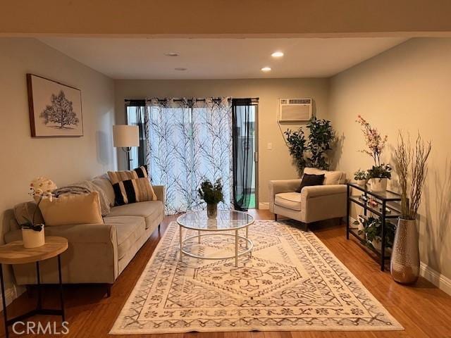 living area featuring wood finished floors, an AC wall unit, recessed lighting, and baseboards