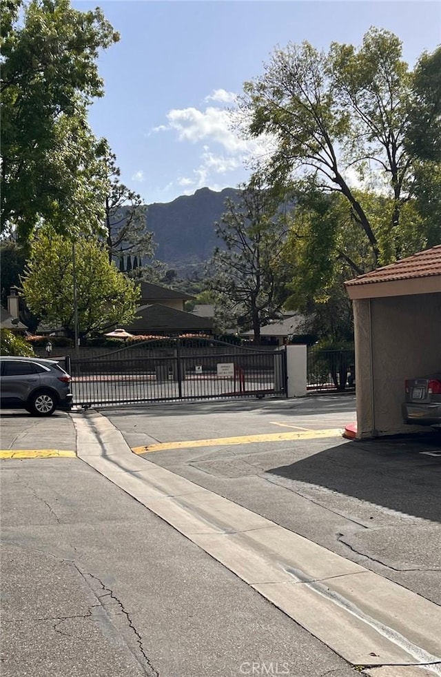 view of asphalt road with a mountain view, a gate, and a gated entry