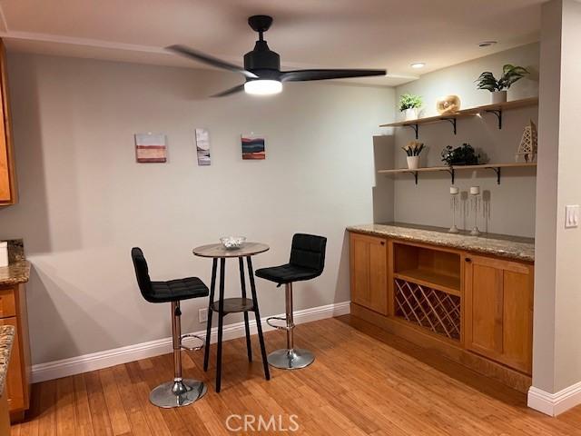 bar featuring light wood-style floors, baseboards, and ceiling fan