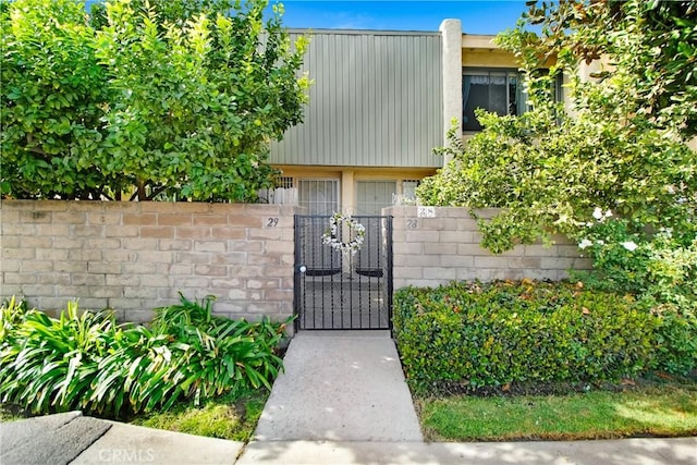 view of exterior entry with a gate, fence, and stucco siding