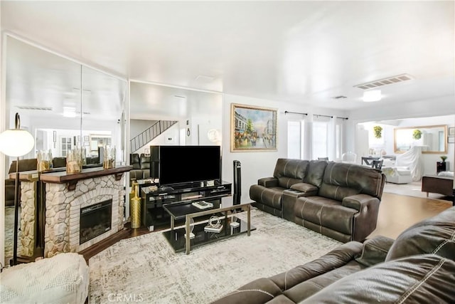 living room featuring visible vents, a fireplace, and wood finished floors