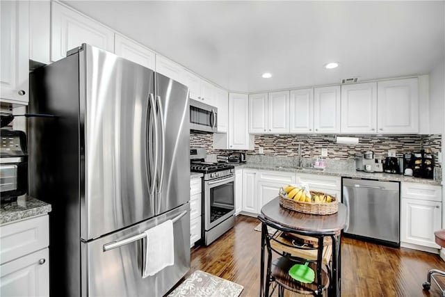 kitchen featuring white cabinets, backsplash, appliances with stainless steel finishes, and a sink